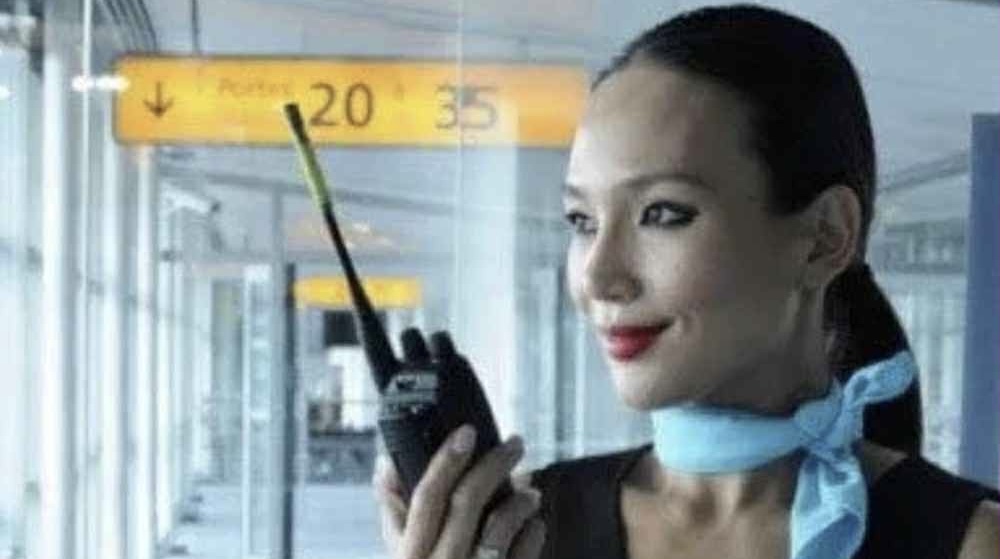 Hôtesse de l’air tenant un talkie-walkie à l’aéroport