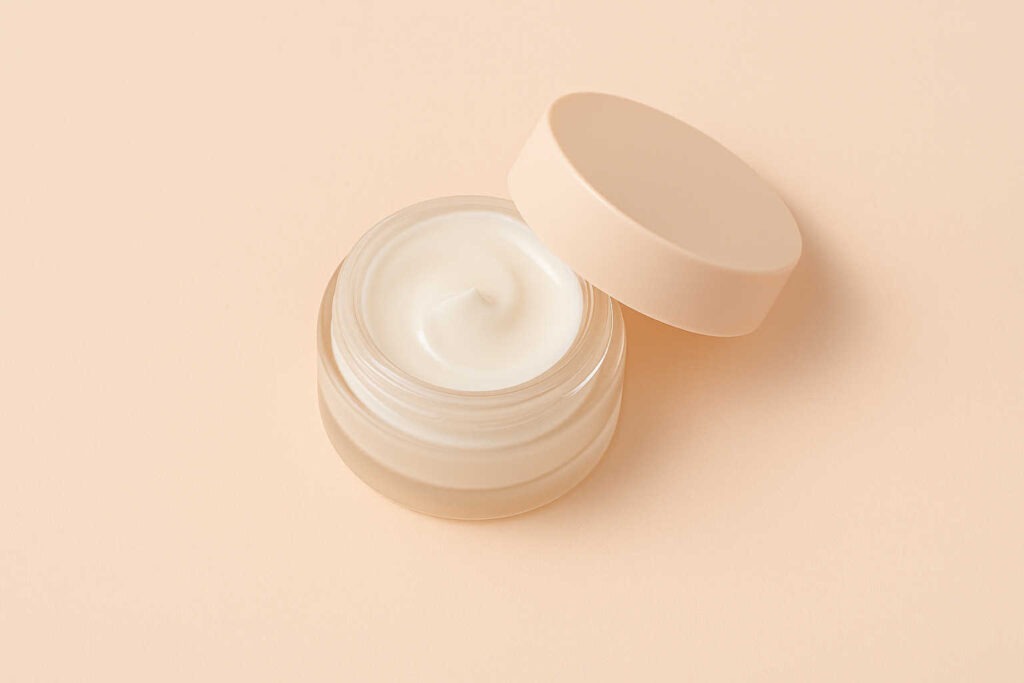 Pot ouvert de crème contour des yeux sur fond beige 