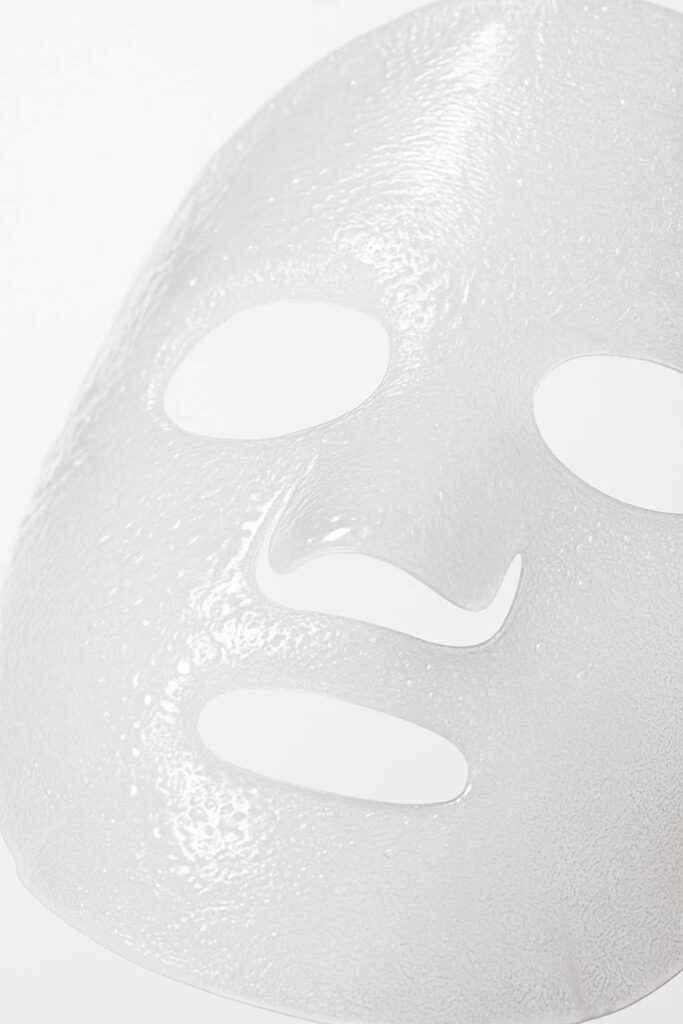 Gros plan d’un masque coréen en bio-cellulose transparent, montrant sa texture gélifiée et hydratante idéale pour les peaux sensibles
