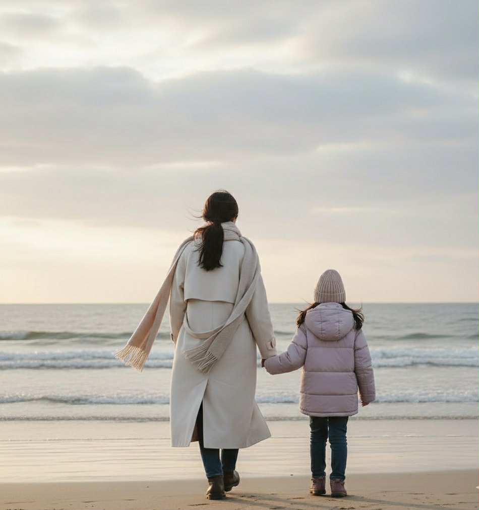 Photo d’une mère et sa fille sur une plage en hiver, utilisée pour illustrer un article sur les rougeurs dues au froid et la routine coréenne minimaliste qui apaise la peau sensible.mère et fille sur la plage en hiver — rougeurs du visage en hiver
