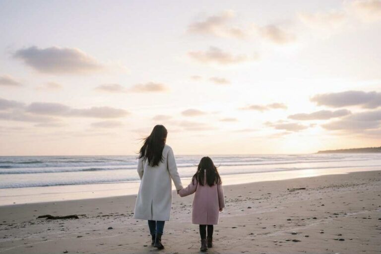 Mère et fille marchant sur une plage en hiver au coucher du soleil, ambiance douce et apaisante.